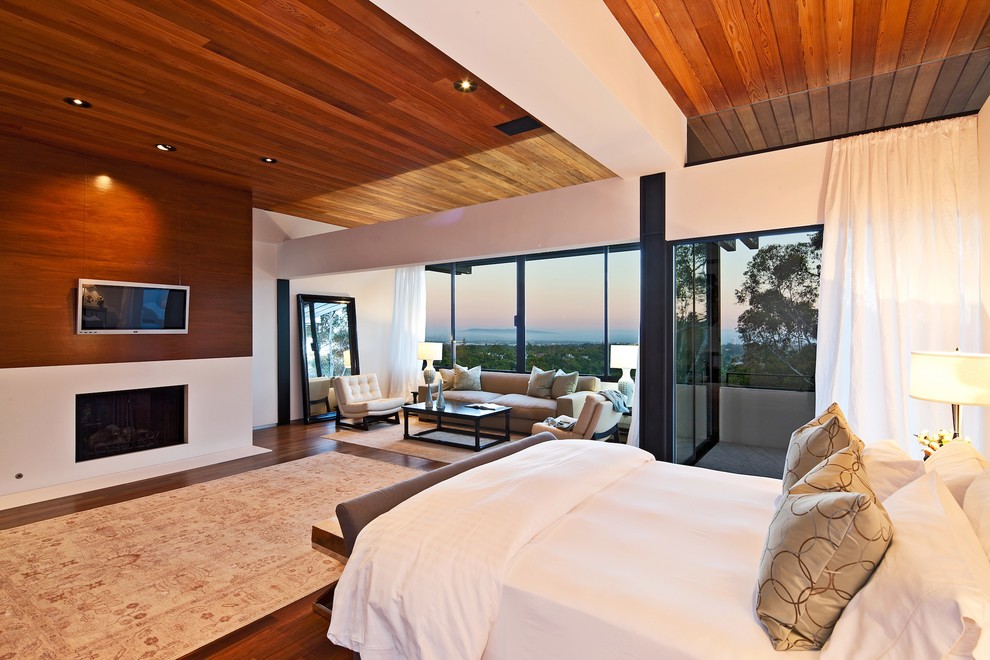 Modern bedroom in Los Angeles with dark hardwood floors and a standard fireplace.