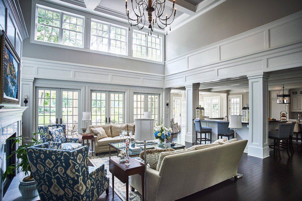 Inspiration for an expansive traditional open concept family room in Philadelphia with dark hardwood floors, a standard fireplace, a wood fireplace surround, no tv and grey walls.