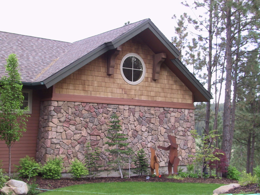 This is an example of a large country two-storey brown house exterior in Seattle with stone veneer, a gable roof and a shingle roof.