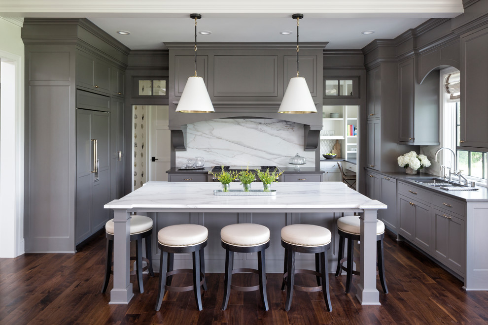 Inspiration for a transitional u-shaped eat-in kitchen in Minneapolis with an undermount sink, recessed-panel cabinets, grey cabinets, white splashback, stone slab splashback, panelled appliances, dark hardwood floors, with island, brown floor and white benchtop.