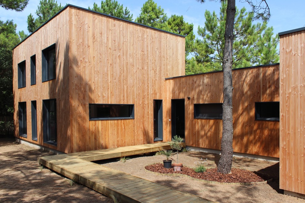 This is an example of a contemporary exterior in Nantes with wood siding and a flat roof.