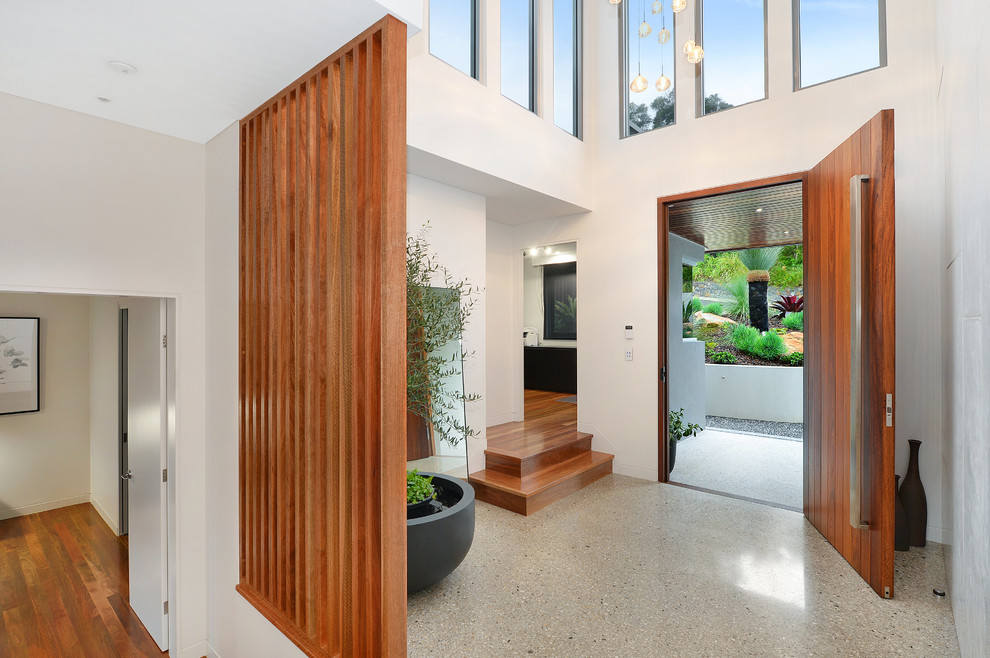 This is an example of a contemporary foyer in Wollongong with white walls, a single front door, a medium wood front door and beige floor.