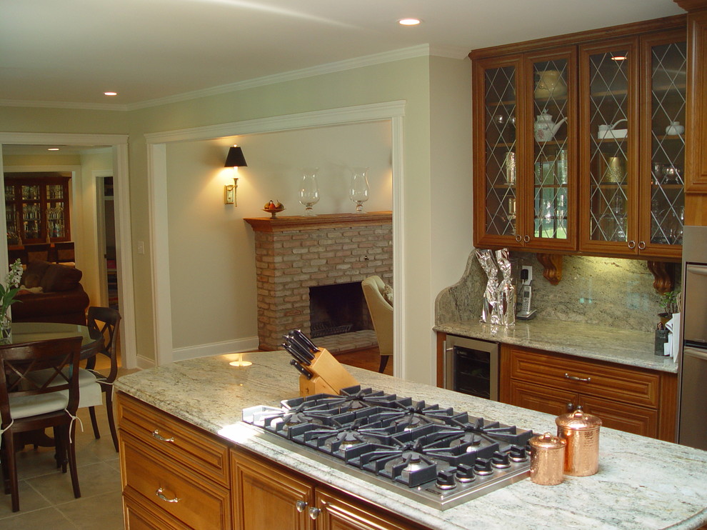 Photo of a mid-sized traditional l-shaped eat-in kitchen in New York with an undermount sink, raised-panel cabinets, dark wood cabinets, granite benchtops, beige splashback, stone slab splashback, stainless steel appliances, ceramic floors and with island.