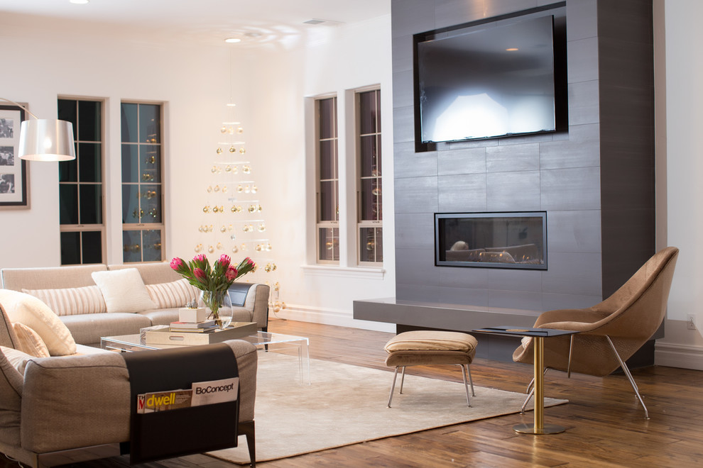 This is an example of a modern family room in Sacramento with white walls, medium hardwood floors, a tile fireplace surround and a wall-mounted tv.