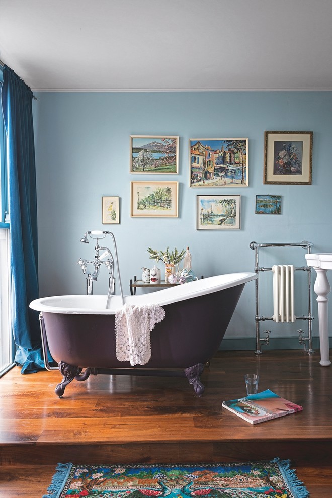 Mid-sized traditional bathroom in London with a claw-foot tub, blue walls and dark hardwood floors.