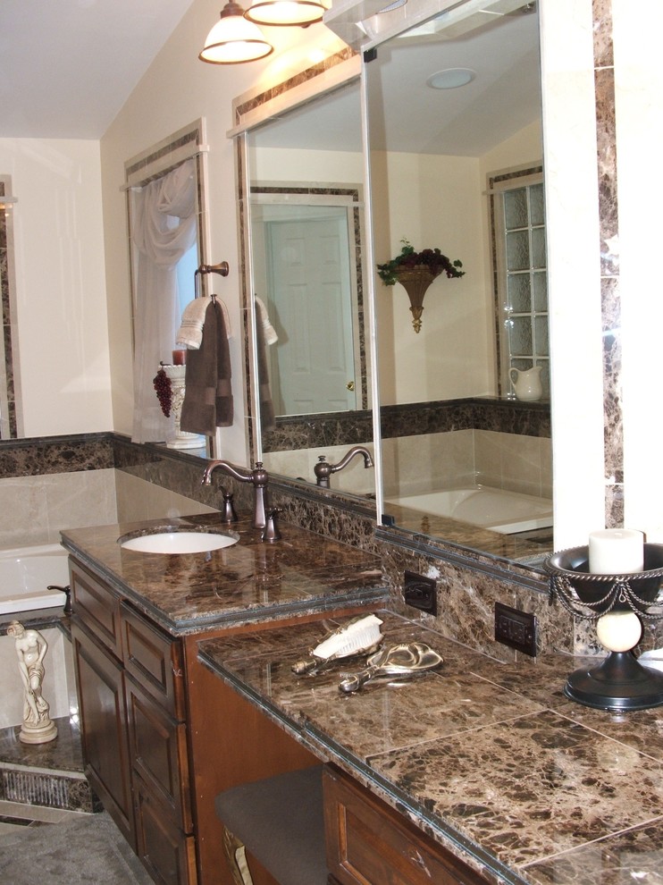 Inspiration for a mid-sized transitional master beige tile and porcelain tile porcelain tile and beige floor drop-in bathtub remodel with raised-panel cabinets, dark wood cabinets, a two-piece toilet, beige walls, an undermount sink, granite countertops and a hinged shower door