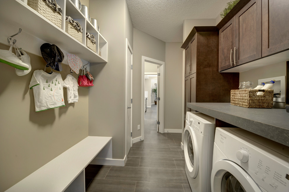 Design ideas for a mid-sized transitional galley dedicated laundry room in Edmonton with shaker cabinets, dark wood cabinets, laminate benchtops, beige walls, ceramic floors, a side-by-side washer and dryer and grey floor.