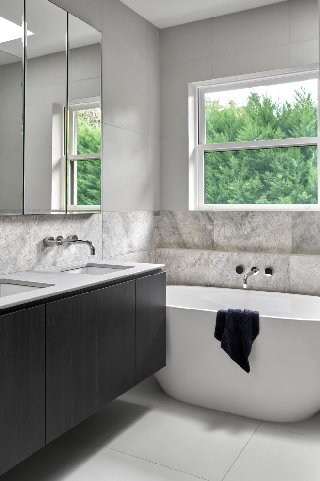 Design ideas for a small contemporary master bathroom in Melbourne with a freestanding tub, gray tile, stone tile, grey walls, ceramic floors, an undermount sink, solid surface benchtops, grey floor, grey benchtops, a double vanity, a floating vanity, flat-panel cabinets and black cabinets.