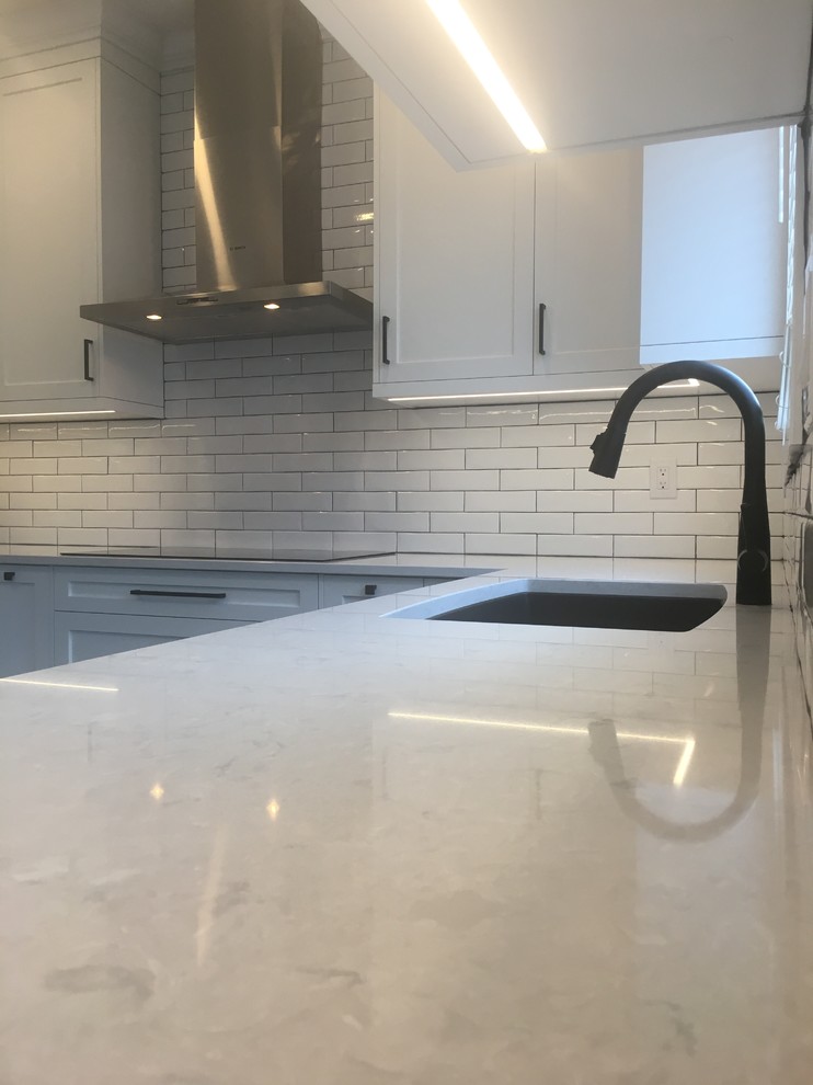 Mid-sized contemporary kitchen in Toronto with shaker cabinets, white cabinets, quartz benchtops, white splashback, subway tile splashback and stainless steel appliances.