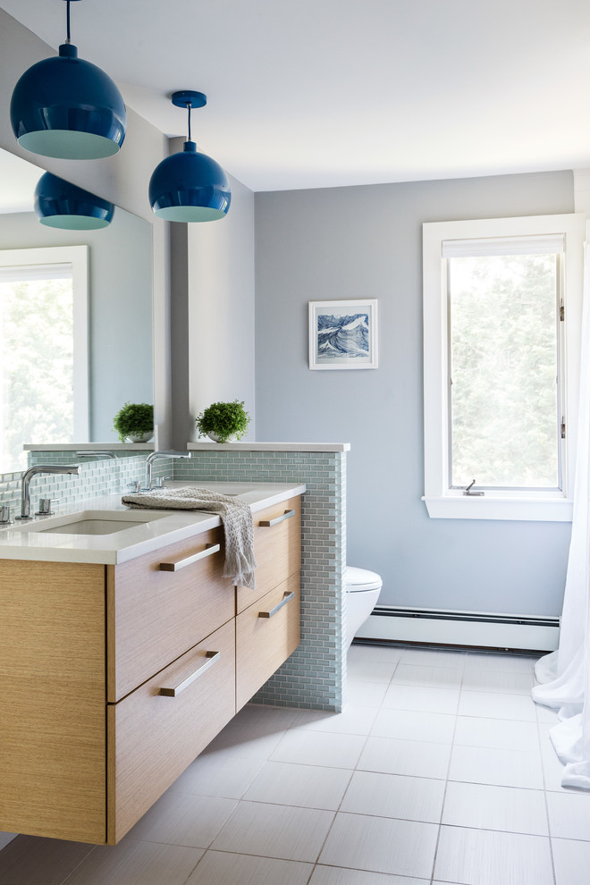 This is an example of a transitional 3/4 bathroom in Boston with flat-panel cabinets, medium wood cabinets, gray tile, grey walls, an undermount sink and white benchtops.