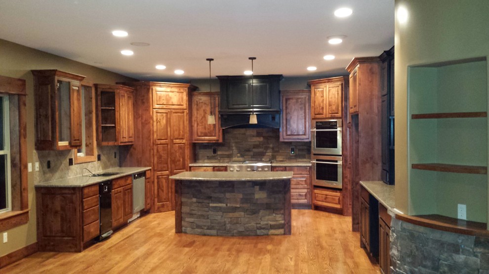 Inredning av ett rustikt mellanstort grå grått kök, med en undermonterad diskho, luckor med upphöjd panel, skåp i ljust trä, granitbänkskiva, flerfärgad stänkskydd, stänkskydd i stenkakel, rostfria vitvaror, ljust trägolv, en köksö och brunt golv