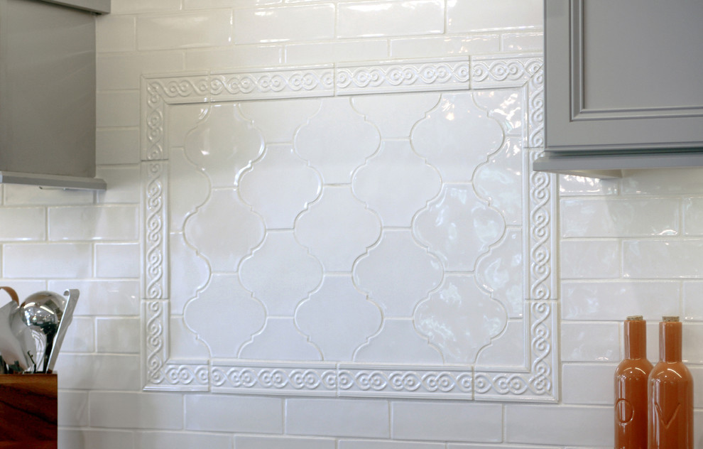 Example of a large transitional l-shaped porcelain tile eat-in kitchen design with a farmhouse sink, recessed-panel cabinets, gray cabinets, granite countertops, white backsplash, ceramic backsplash, stainless steel appliances and an island