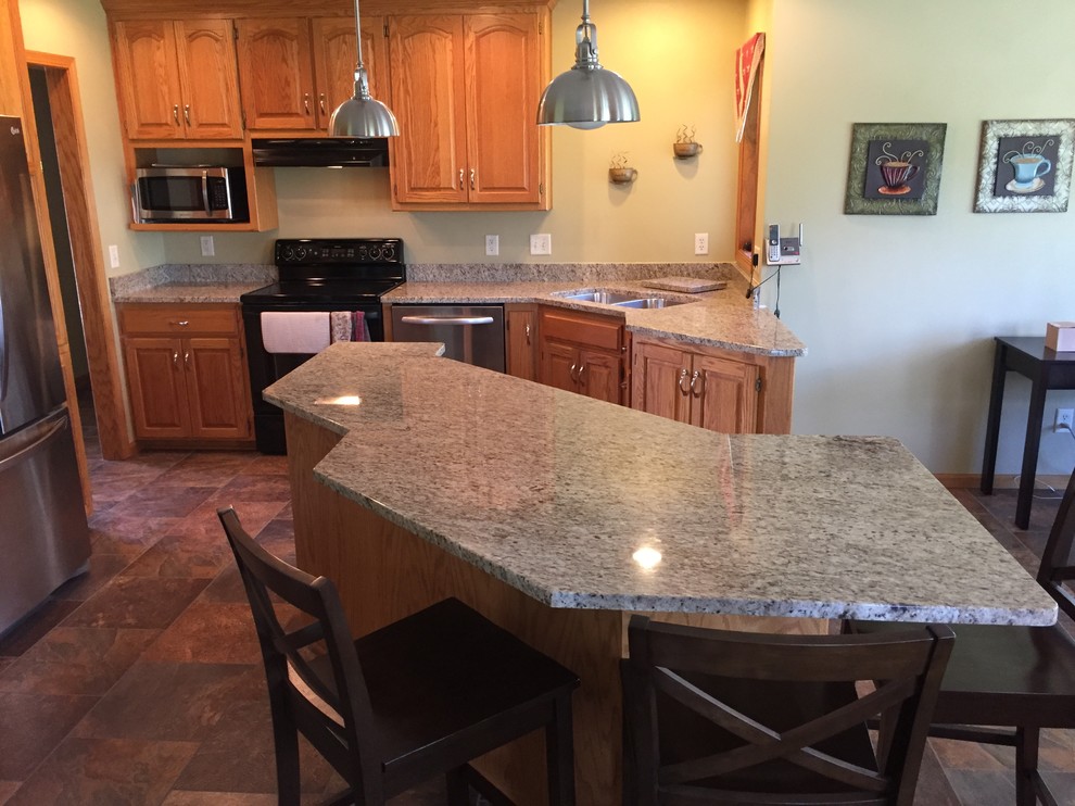 Example of a classic porcelain tile eat-in kitchen design with an undermount sink, granite countertops, black backsplash, stone slab backsplash and an island