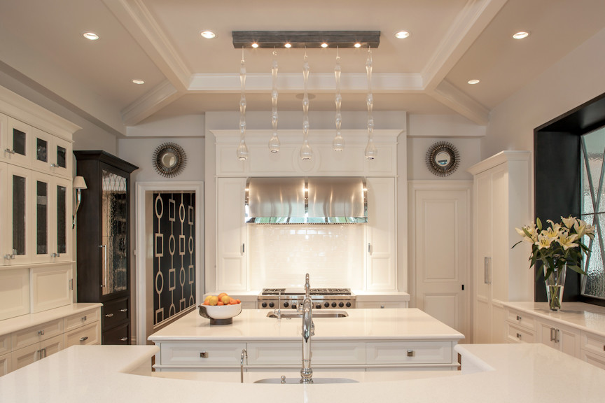 Example of a transitional u-shaped kitchen pantry design in Miami with an undermount sink, recessed-panel cabinets, white cabinets, quartzite countertops, white backsplash, stone slab backsplash, stainless steel appliances and two islands