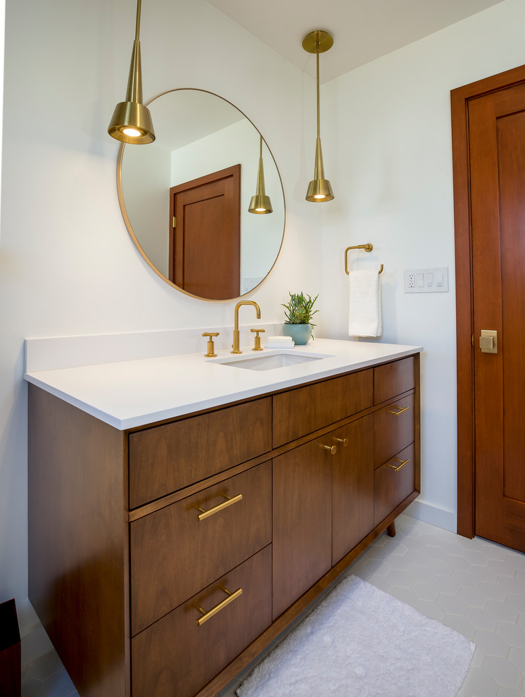 Photo of a mid-sized midcentury bathroom in Los Angeles with medium wood cabinets, a shower/bathtub combo, white tile, ceramic tile, white walls, engineered quartz benchtops, a drop-in tub, a two-piece toilet, porcelain floors, an undermount sink, white floor, a hinged shower door and flat-panel cabinets.