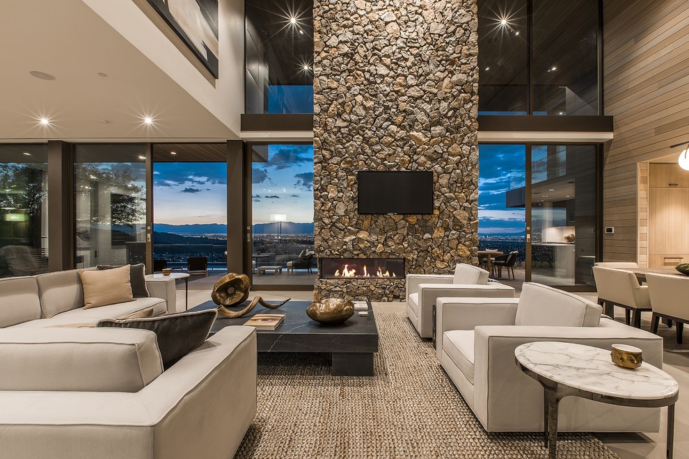 Contemporary open concept living room in Las Vegas with beige walls, concrete floors, a ribbon fireplace, a stone fireplace surround, a wall-mounted tv and grey floor.
