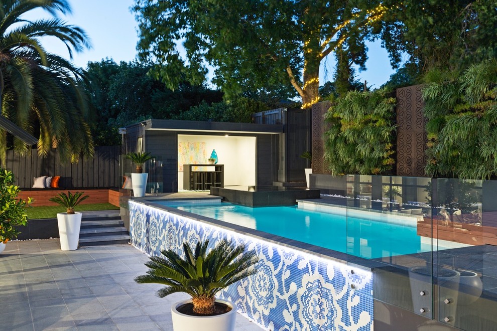 This is an example of a mid-sized contemporary backyard custom-shaped infinity pool in Melbourne with natural stone pavers.