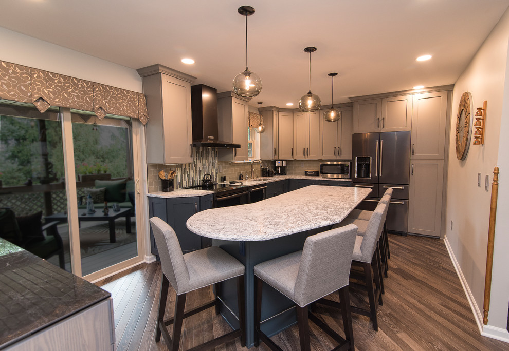 Example of a mid-sized transitional l-shaped brown floor eat-in kitchen design in Baltimore with a single-bowl sink, shaker cabinets, gray cabinets, quartz countertops, gray backsplash, subway tile backsplash, stainless steel appliances, an island and white countertops