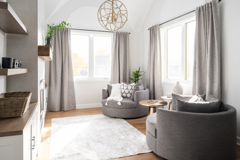 Inspiration for an expansive contemporary master bedroom in Montreal with grey walls, light hardwood floors, a standard fireplace, brown floor and vaulted.