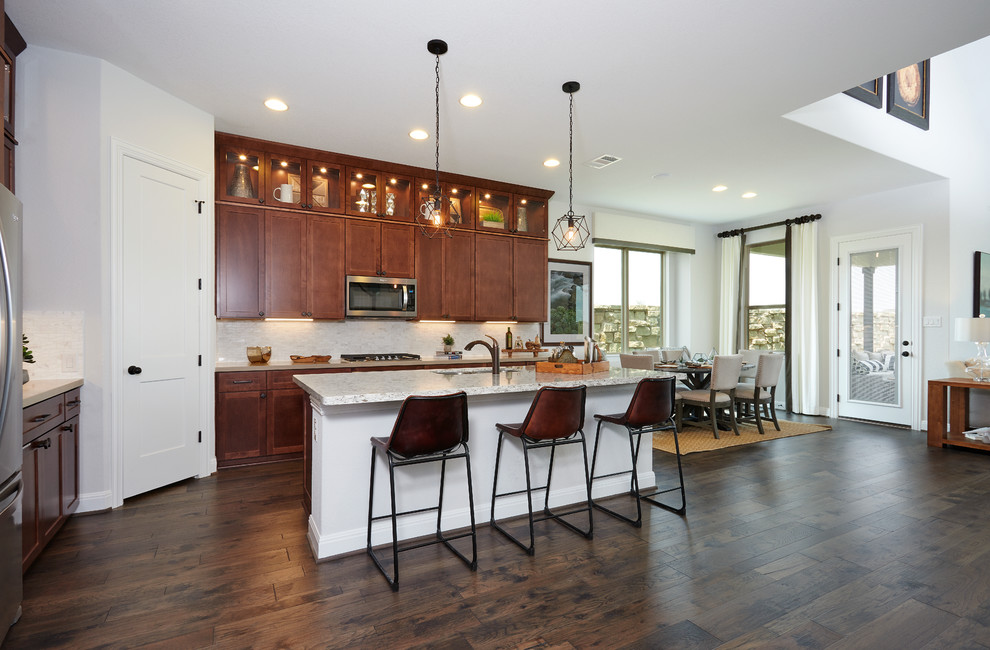 Design ideas for a large contemporary l-shaped eat-in kitchen in Austin with a double-bowl sink, recessed-panel cabinets, medium wood cabinets, limestone benchtops, beige splashback, glass sheet splashback, stainless steel appliances, dark hardwood floors, with island, brown floor and beige benchtop.