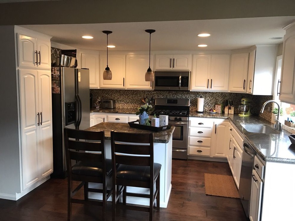 Traditional kitchen in Los Angeles with raised-panel cabinets, white cabinets, granite benchtops, grey splashback, stainless steel appliances, dark hardwood floors, with island, brown floor and grey benchtop.