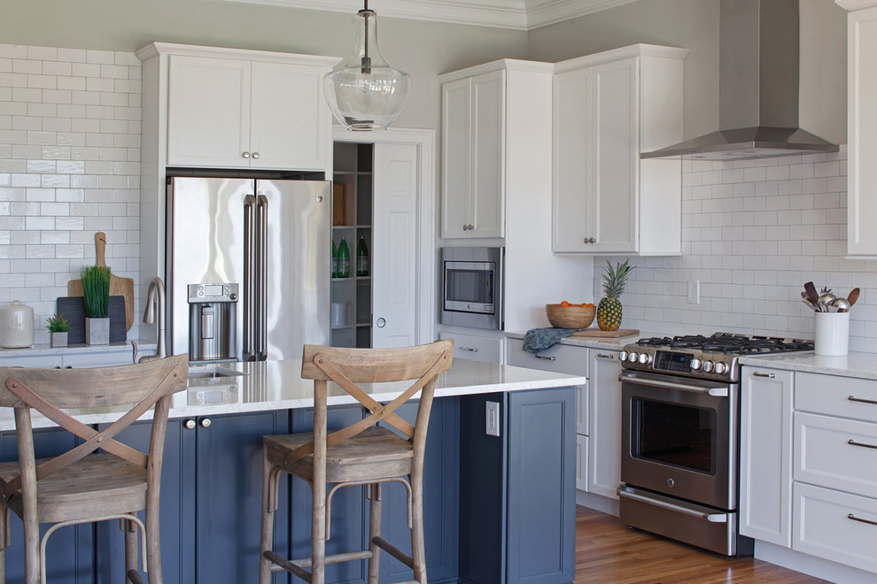 Open concept kitchen - large transitional l-shaped medium tone wood floor and brown floor open concept kitchen idea with an undermount sink, shaker cabinets, blue cabinets, quartz countertops, white backsplash, subway tile backsplash, stainless steel appliances, an island and white countertops