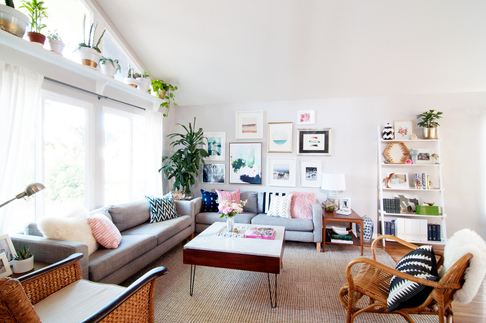 This is an example of an eclectic open concept living room in Los Angeles with no fireplace, no tv, a library, white walls and medium hardwood floors.
