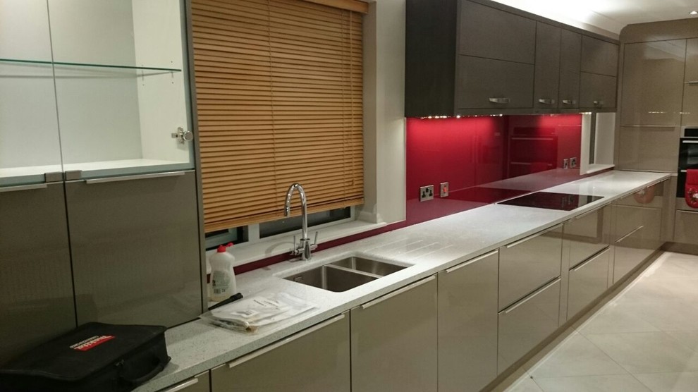Inspiration for a large contemporary u-shaped eat-in kitchen in Dublin with an undermount sink, beige cabinets, recycled glass benchtops, red splashback, glass tile splashback, white appliances, ceramic floors and no island.