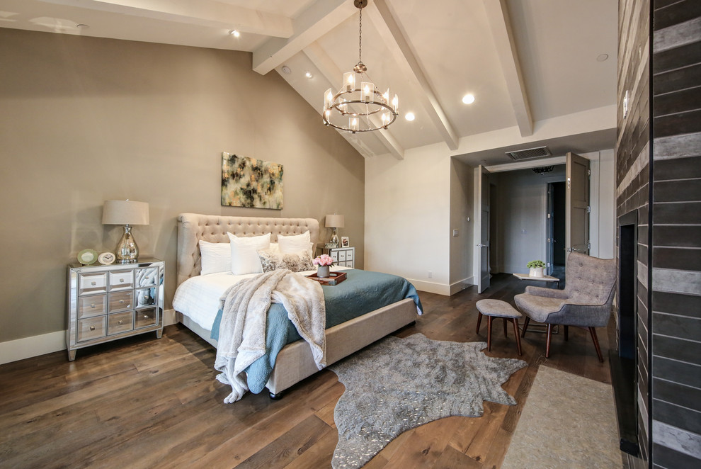 This is an example of a transitional master bedroom in Phoenix with beige walls, medium hardwood floors, a standard fireplace, a tile fireplace surround and brown floor.