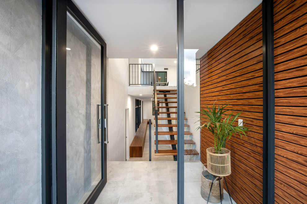Large beach style front door in Sunshine Coast with multi-coloured walls, porcelain floors, a single front door, a glass front door and grey floor.