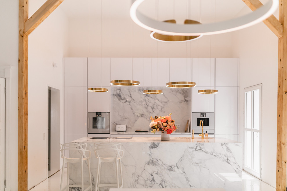 Photo of a large contemporary galley eat-in kitchen in Cologne with an integrated sink, flat-panel cabinets, white cabinets, marble benchtops, white splashback, ceramic splashback, white appliances, with island, white floor and white benchtop.