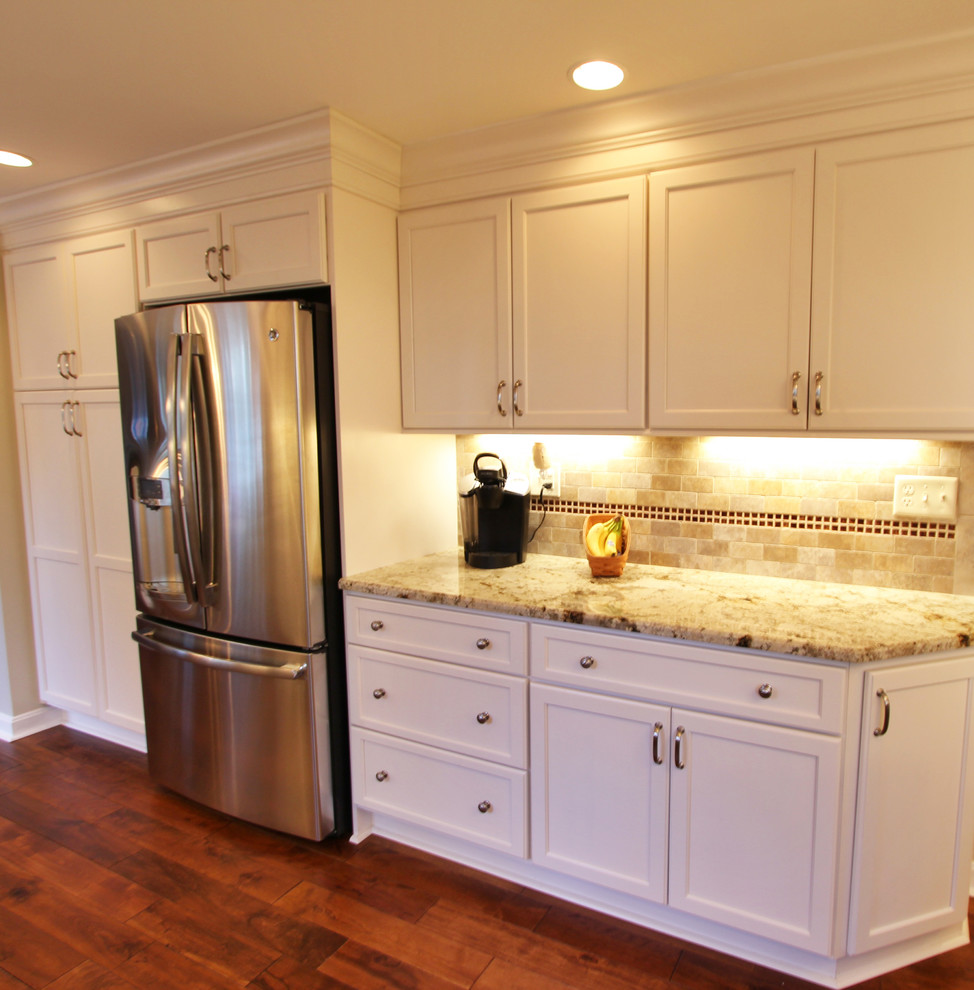 Eat-in kitchen - large medium tone wood floor eat-in kitchen idea with a double-bowl sink, white cabinets, granite countertops, white backsplash, glass tile backsplash, stainless steel appliances and no island