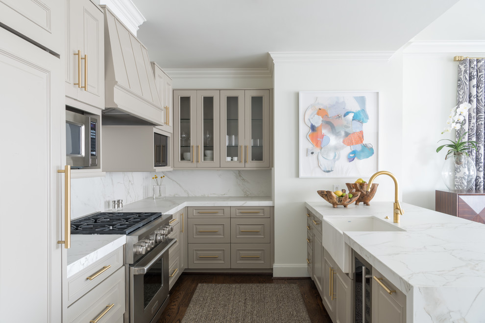 Photo of a transitional u-shaped kitchen in Dallas with a farmhouse sink, raised-panel cabinets, grey cabinets, white splashback, stone slab splashback, stainless steel appliances, dark hardwood floors, a peninsula and brown floor.