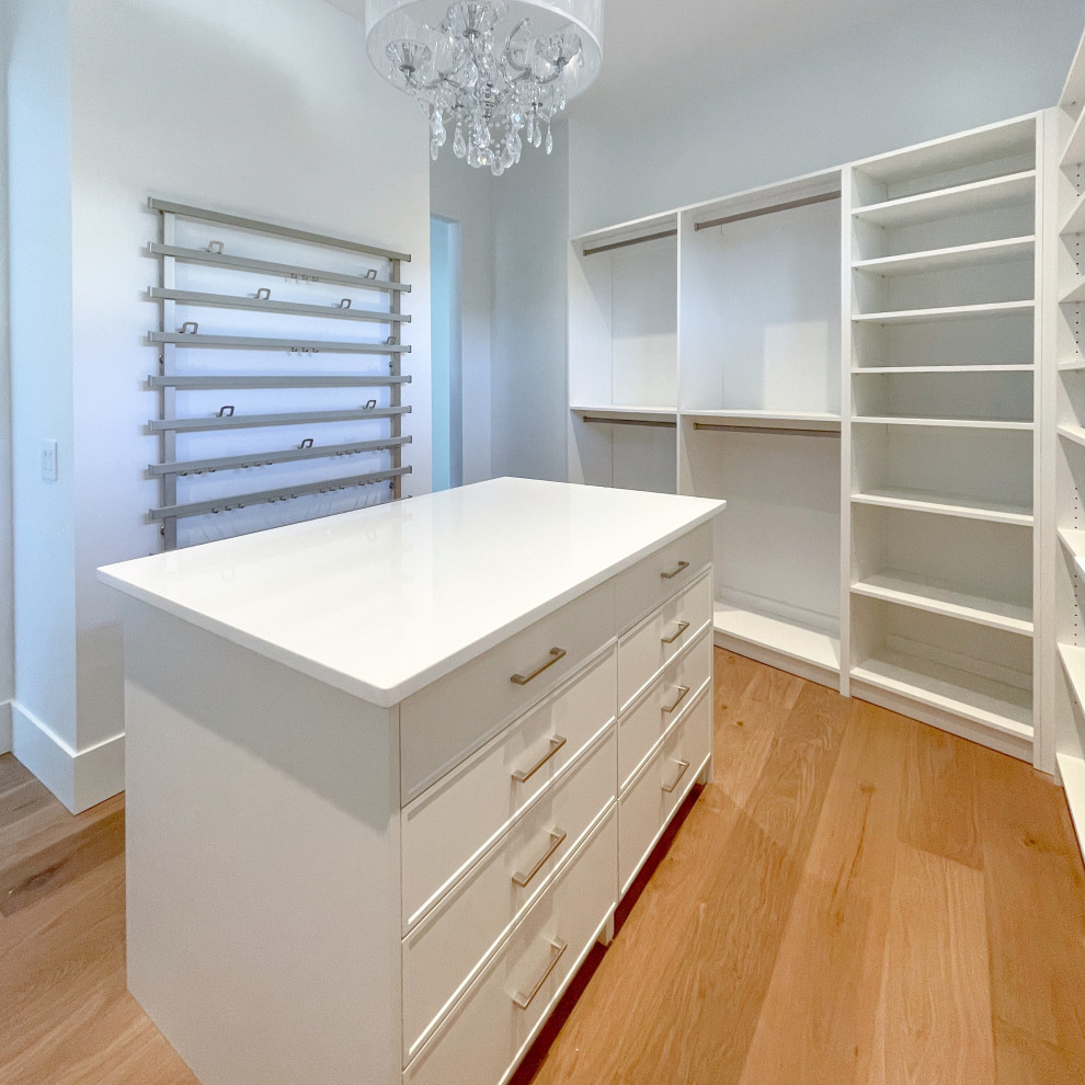 Modelo de armario vestidor abovedado tradicional renovado grande con armarios estilo shaker, puertas de armario blancas y suelo de madera clara