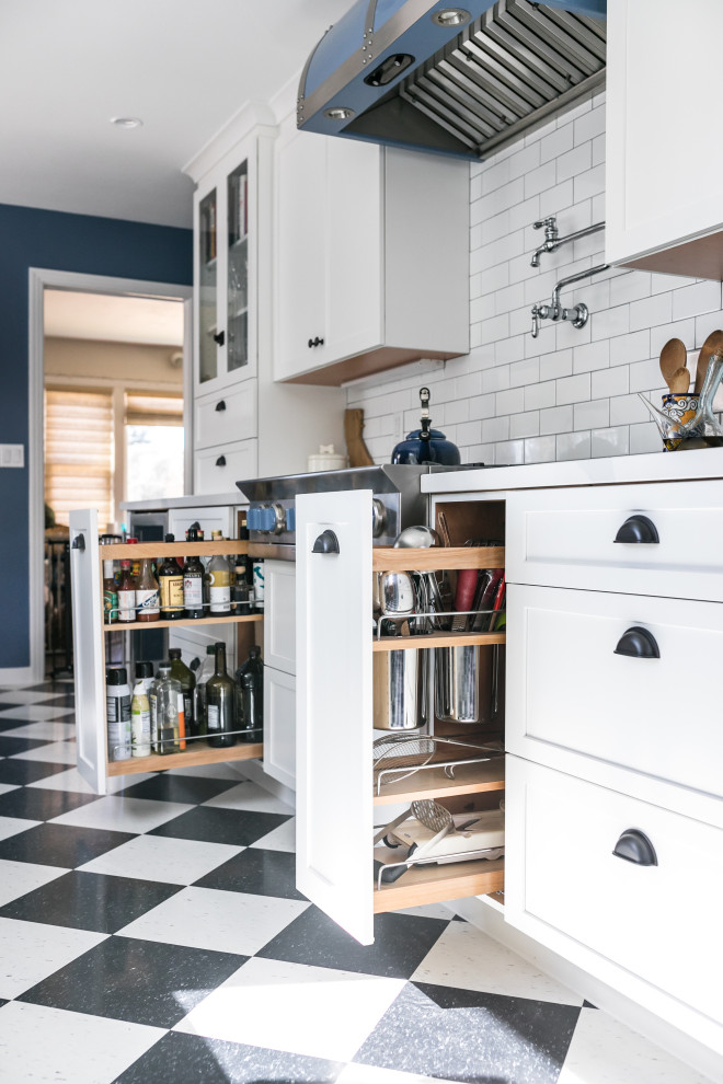 Design ideas for a mid-sized eclectic galley eat-in kitchen in San Francisco with a farmhouse sink, shaker cabinets, white cabinets, quartz benchtops, white splashback, ceramic splashback, coloured appliances, vinyl floors, no island, black floor and white benchtop.