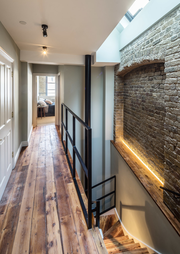 Inspiration for a mid-sized industrial hallway in London with grey walls, light hardwood floors and brown floor.