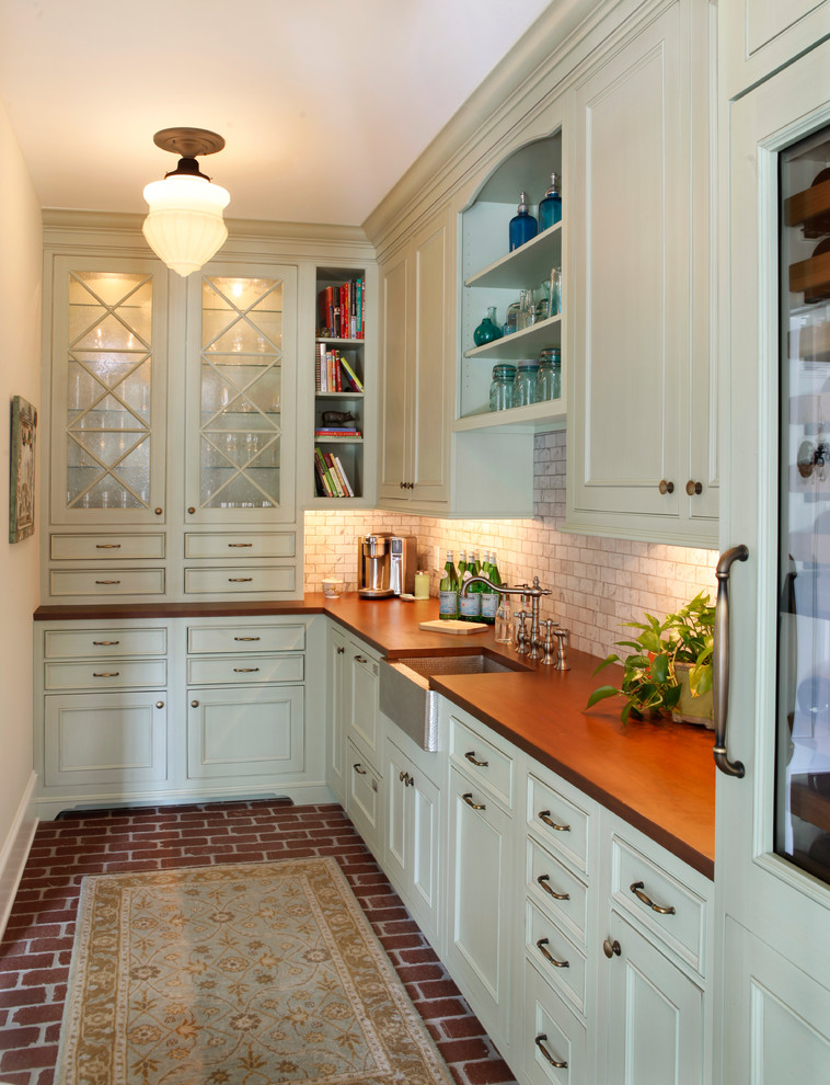 Inspiration for a traditional l-shaped wet bar in Philadelphia with an undermount sink, recessed-panel cabinets, white cabinets, wood benchtops, white splashback, stone tile splashback, brick floors, red floor and brown benchtop.