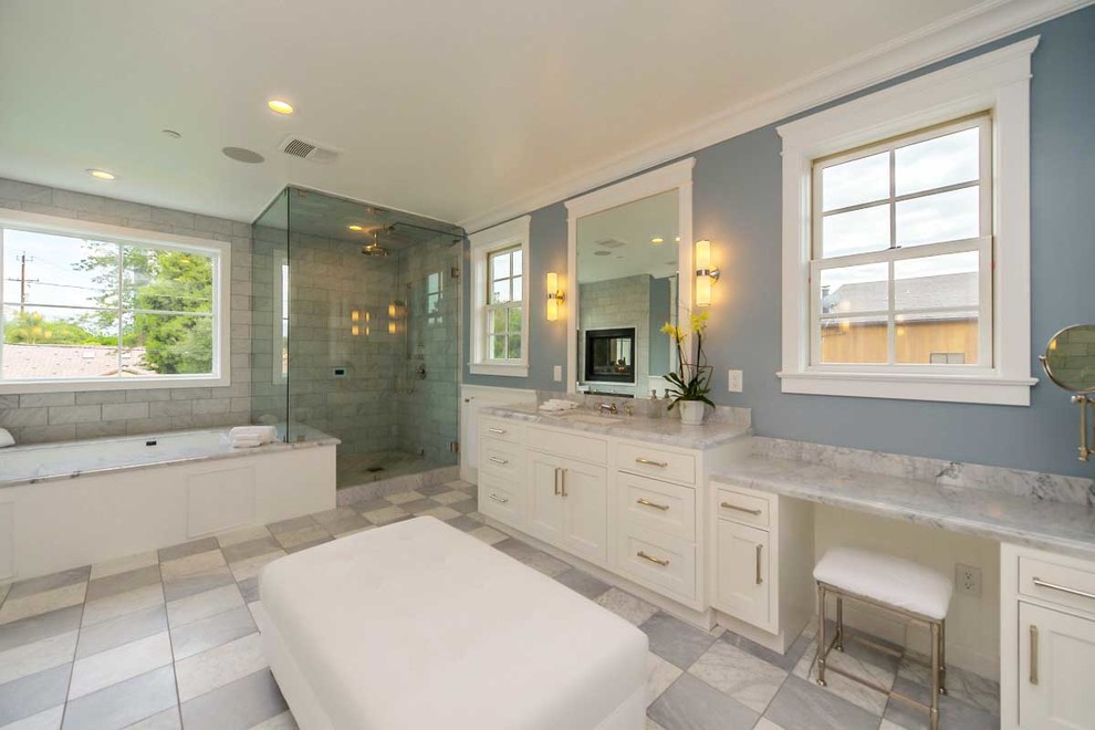 Photo of a traditional bathroom in Los Angeles with recessed-panel cabinets, white cabinets, a drop-in tub, an undermount sink, a hinged shower door and white benchtops.