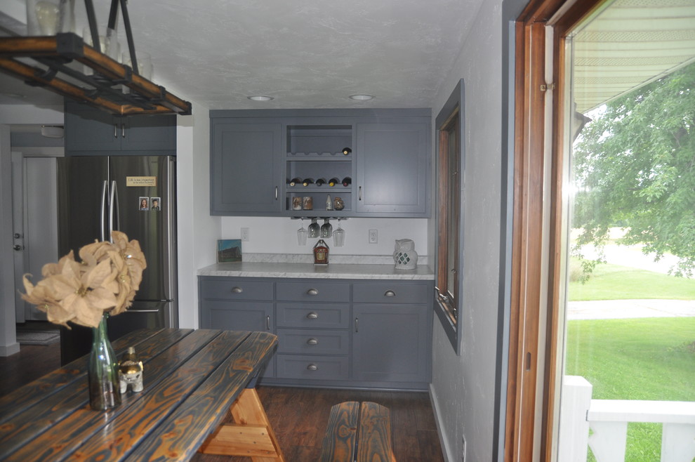 Mid-sized transitional l-shaped medium tone wood floor and brown floor eat-in kitchen photo with a double-bowl sink, shaker cabinets, gray cabinets, marble countertops, white backsplash, stainless steel appliances, an island and gray countertops