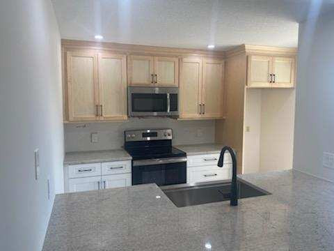 Small transitional vinyl floor kitchen photo in Miami with a farmhouse sink, granite countertops, gray backsplash, glass tile backsplash and gray countertops