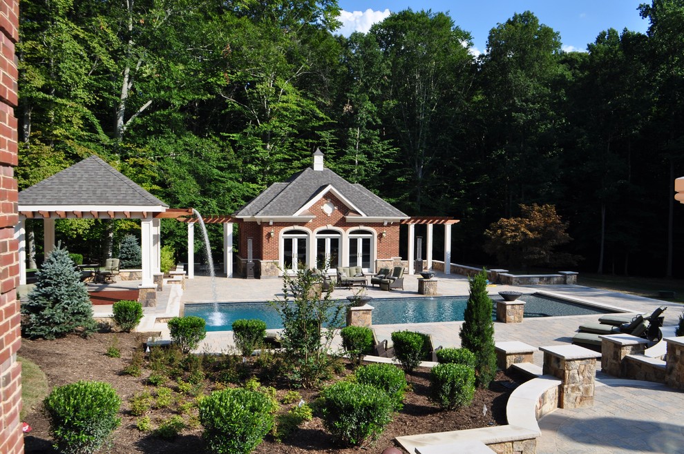 Photo of an expansive traditional backyard rectangular lap pool in DC Metro with a water feature and concrete pavers.