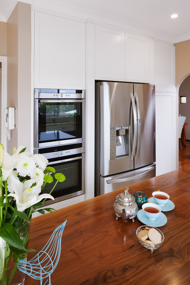 Photo of a traditional kitchen in Perth with shaker cabinets, white cabinets, wood benchtops, stainless steel appliances and with island.