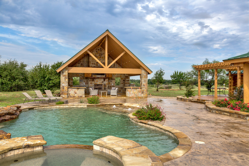 Photo of a mid-sized country backyard custom-shaped pool in Dallas with a hot tub and stamped concrete.