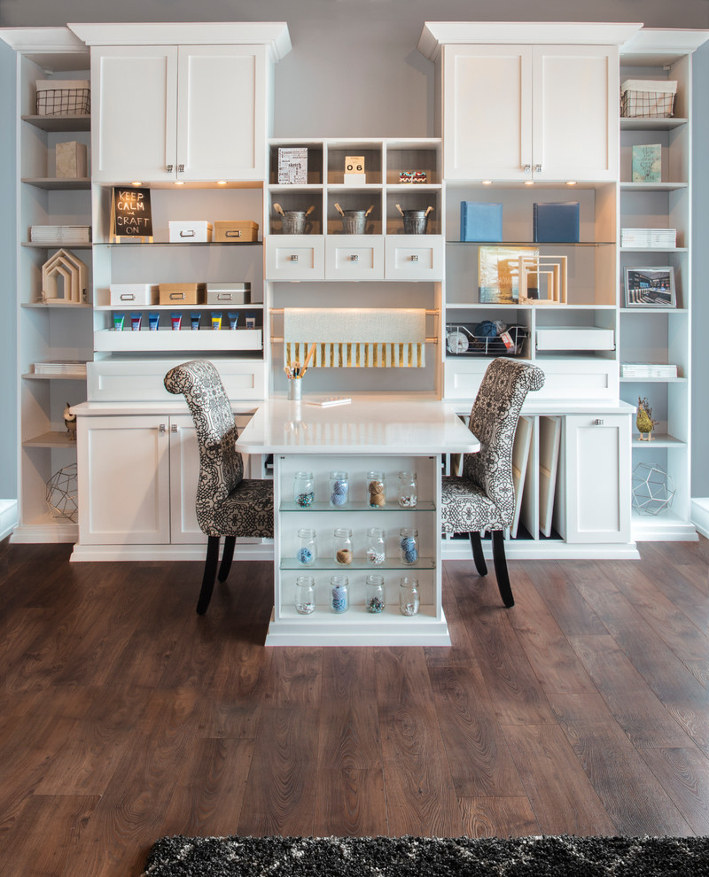 Photo of a large transitional craft room in Chicago with grey walls, medium hardwood floors, no fireplace, a built-in desk and brown floor.