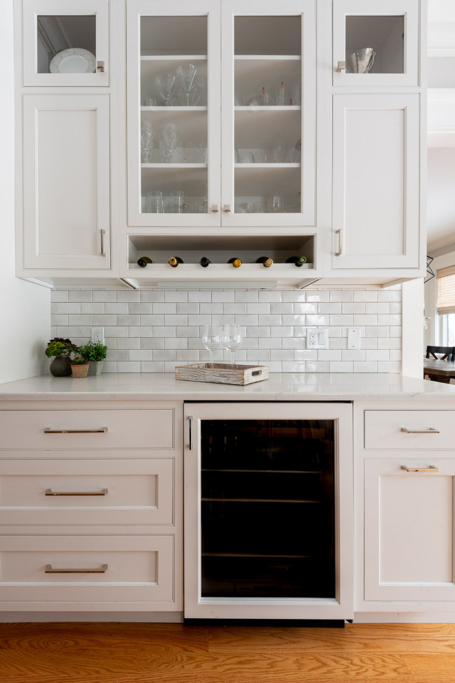 Large transitional u-shaped medium tone wood floor and brown floor eat-in kitchen photo in Boston with an undermount sink, shaker cabinets, white cabinets, quartz countertops, gray backsplash, subway tile backsplash, stainless steel appliances, an island and black countertops