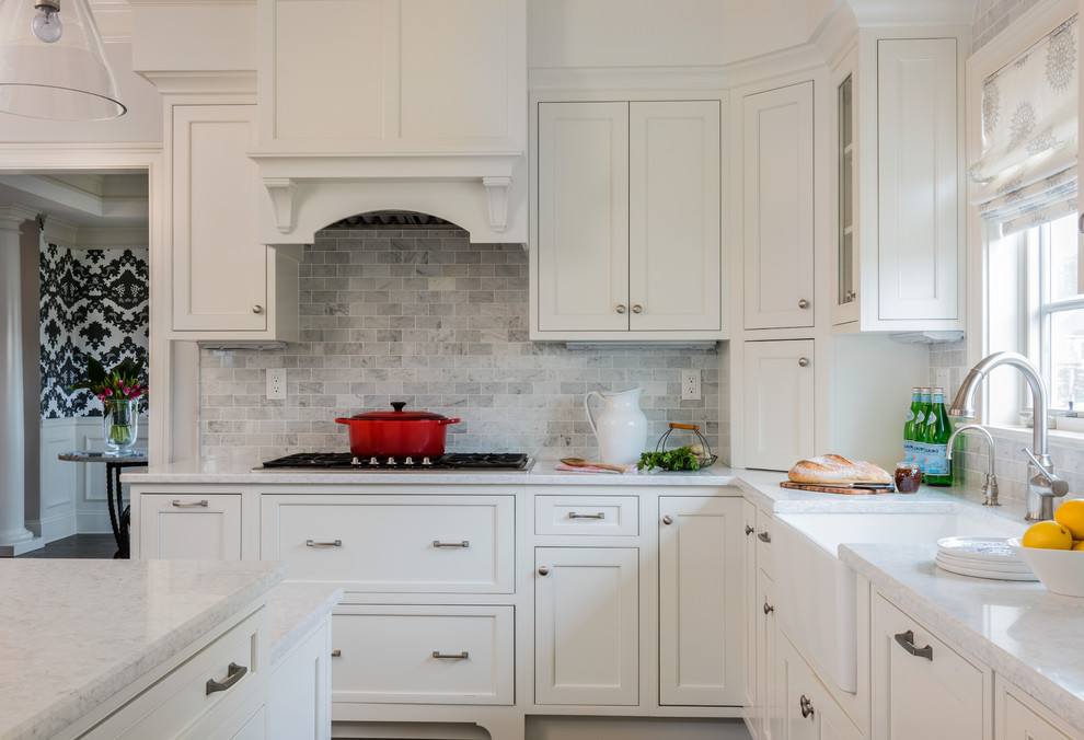 Mid-sized elegant l-shaped dark wood floor and brown floor open concept kitchen photo in Boston with a farmhouse sink, beaded inset cabinets, white cabinets, marble countertops, gray backsplash, stone tile backsplash, stainless steel appliances and an island
