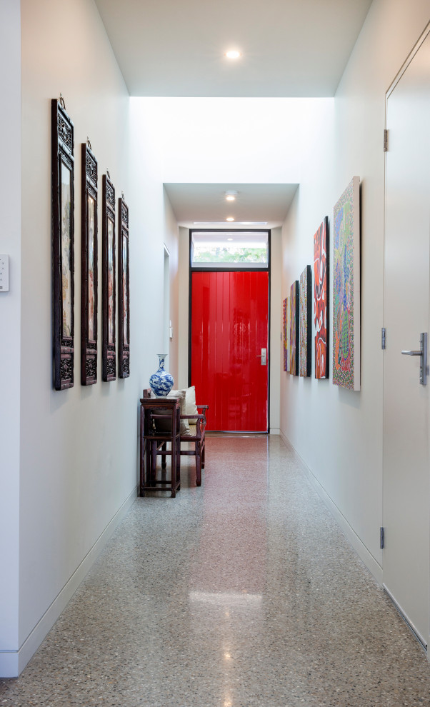 This is an example of a large modern front door in Adelaide with white walls, concrete floors, a single front door and a red front door.