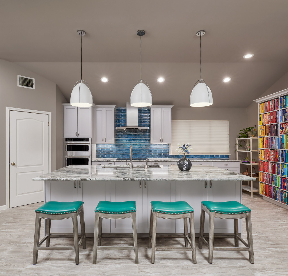 Example of a transitional porcelain tile and gray floor kitchen pantry design with a triple-bowl sink, shaker cabinets, white cabinets, quartzite countertops, blue backsplash, glass tile backsplash, stainless steel appliances, an island and gray countertops