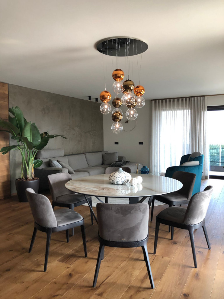 This is an example of a mid-sized contemporary dining room in Milan with white walls, light hardwood floors and beige floor.