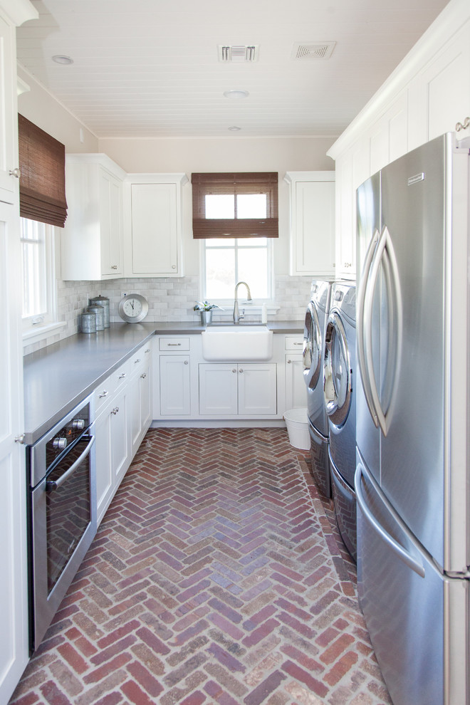 This is an example of a large transitional u-shaped utility room in Phoenix with a farmhouse sink, white cabinets, beige walls, brick floors, a side-by-side washer and dryer and shaker cabinets.
